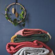 COSY: Coral red parquet merino lambswool throw £83, Cedar green and mustard herringbone throw £59, Rich red herringbone throw £59, Soft grey windmill throw £59 from The British Blanket Company