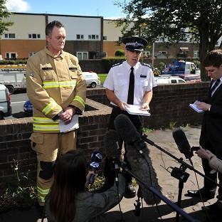 Fire and police officers speak to the media outside the property in Cwmbran where three people died