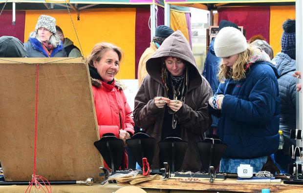 Somerset County Gazette: Three street fair attendees inspect a stall.
