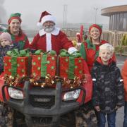 Santa is greeted by two elves and four children after arriving at Rumwell Farm Shop on a quad bike.