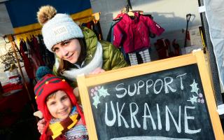 Ksenia Tsikhanovska and Alex Sydorenko in front of a ‘Support Ukraine’ sign at Creech St Michael's Community Christmas Fayre.